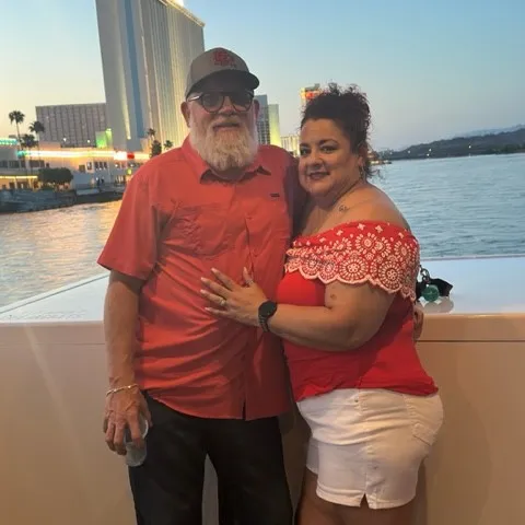 a man and a woman standing in front of a body of water