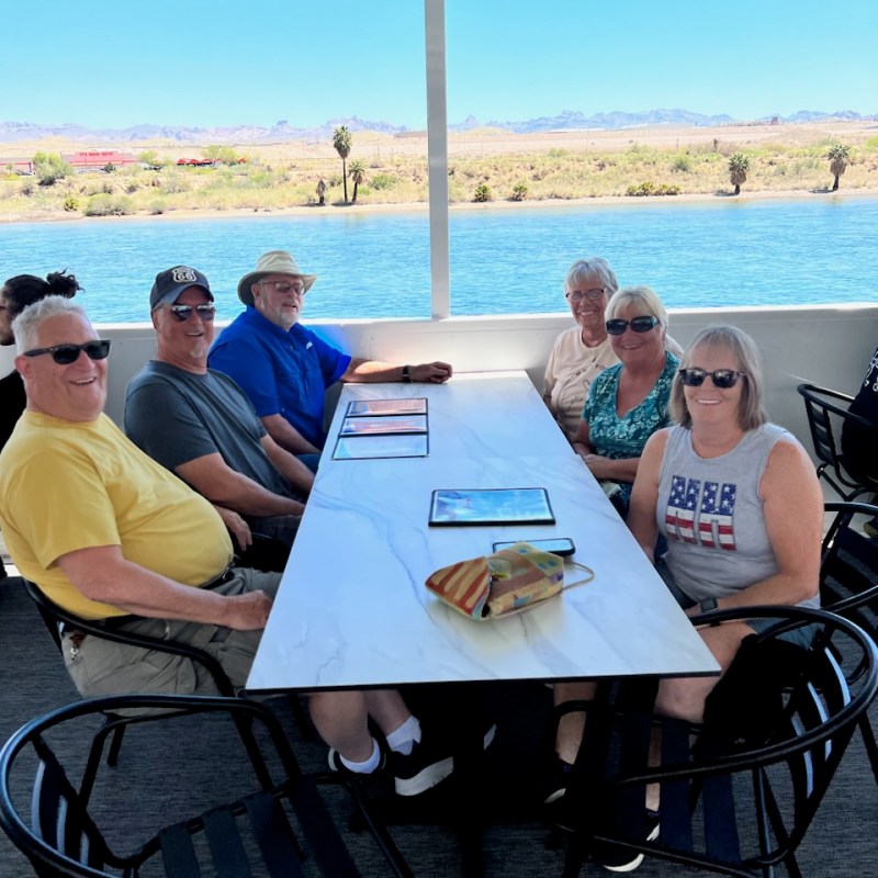 a group of people sitting at a table with a body of water