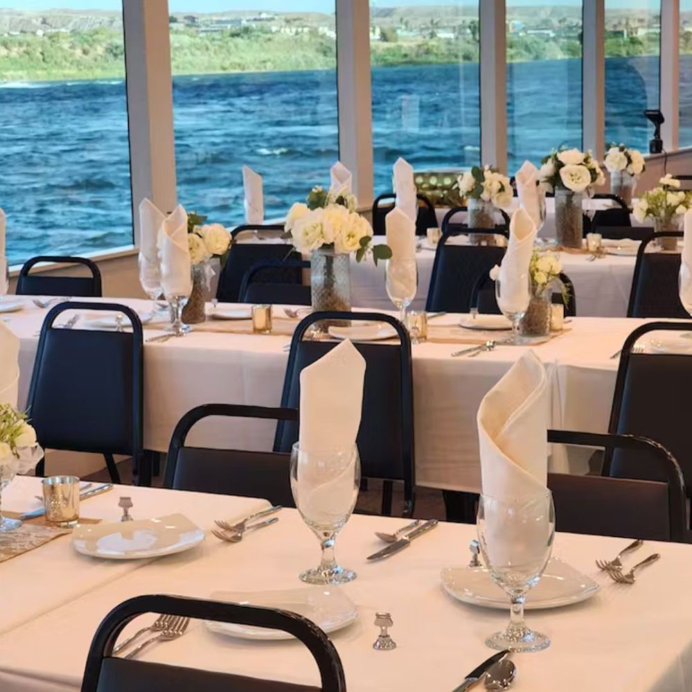 a group of people sitting at a table in front of water