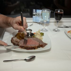 a person holding a plate of food on a table
