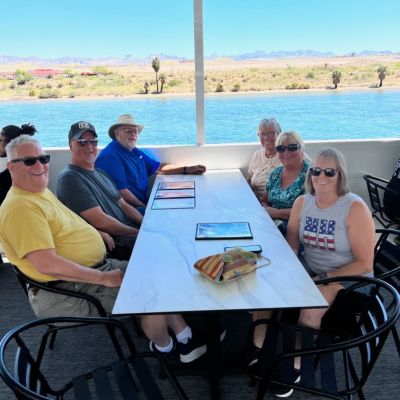 a group of people sitting at a table with a body of water