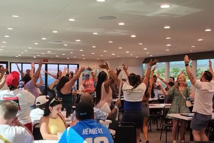 Group of people dancing and raising hands in a well-lit room.