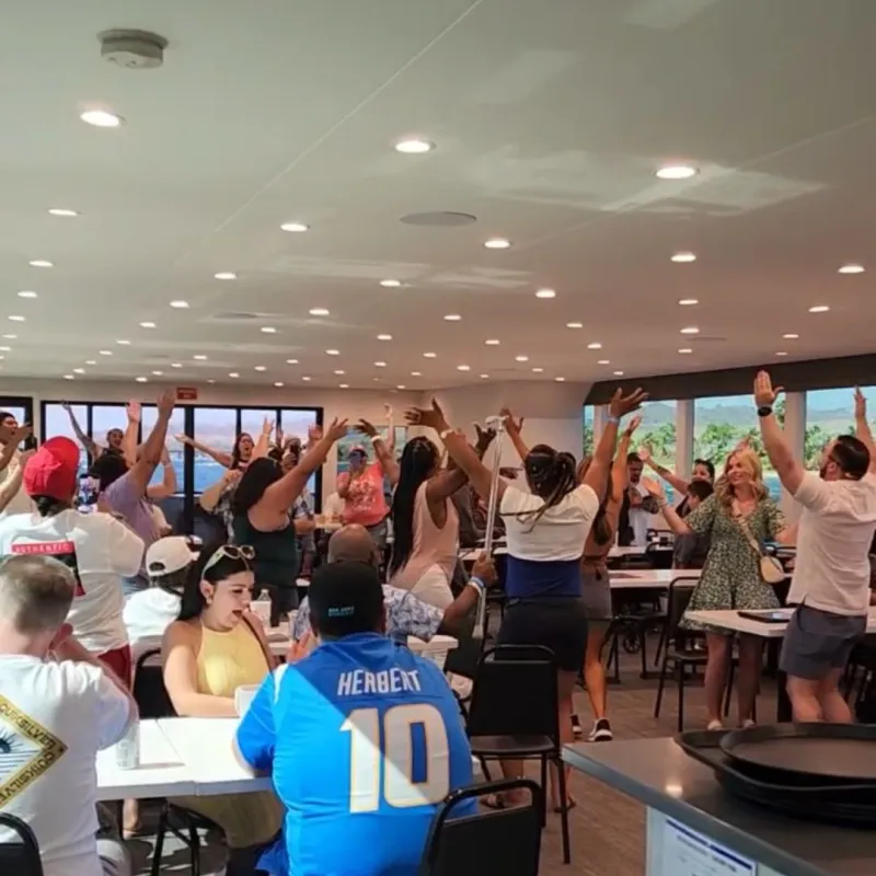 Group of people dancing and raising hands in a well-lit room.