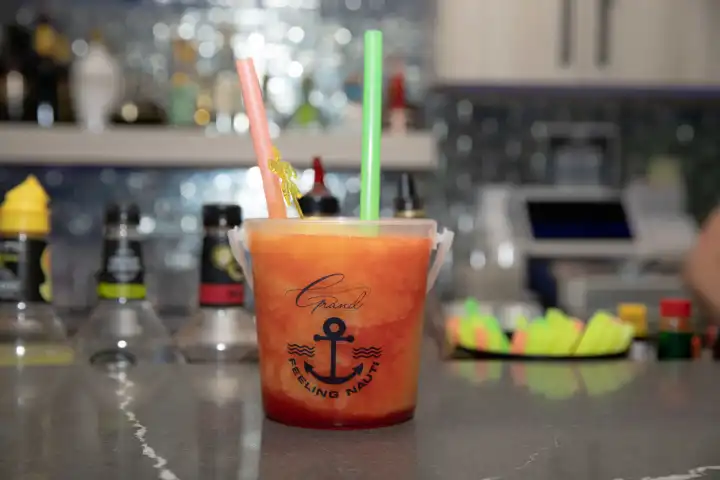 Bucket cocktail with two straws on a bar counter.
