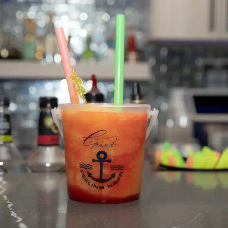 Bucket cocktail with two straws on a bar counter.