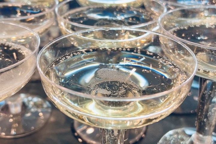 Close-up of multiple champagne glasses with bubbly liquid on a table.