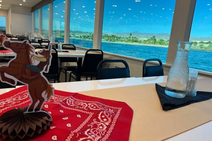 Restaurant with river view, cowboy decor, red bandana, and water pitcher on table.