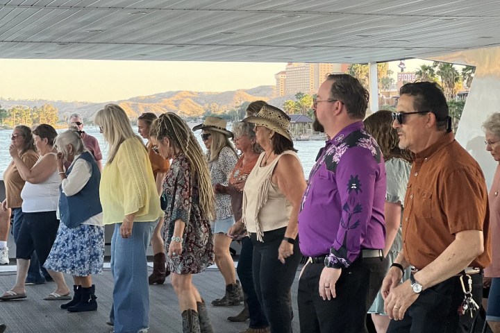 Group of people line dancing indoors under a white ceiling.